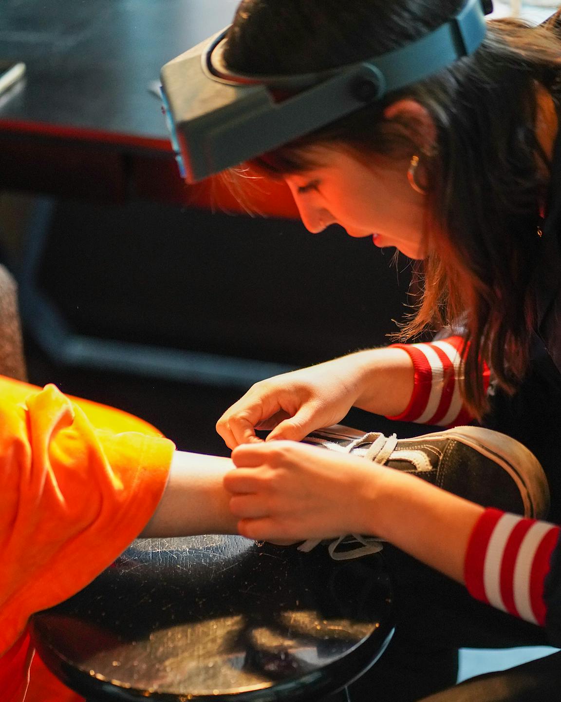 A feminine person holds a chain on someone's ankle.